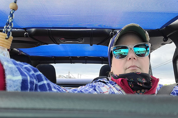 Alina driving in her Jeep wearing sunglasses.