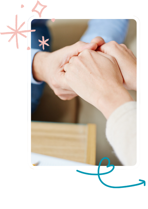 Image of two people holding hands in a warm room.